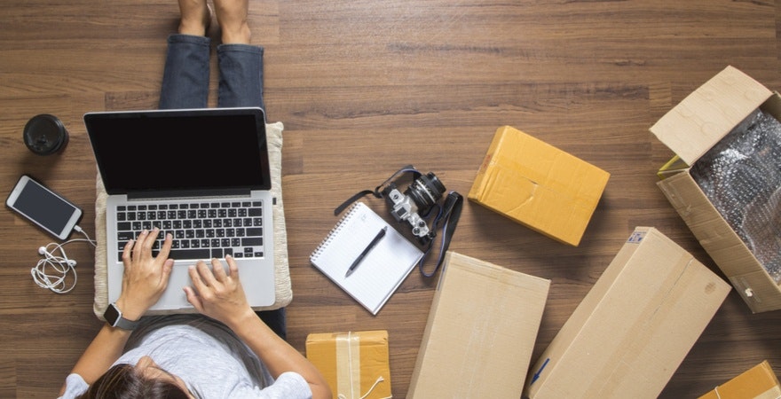 女人在电脑上打字,身边放着包裹